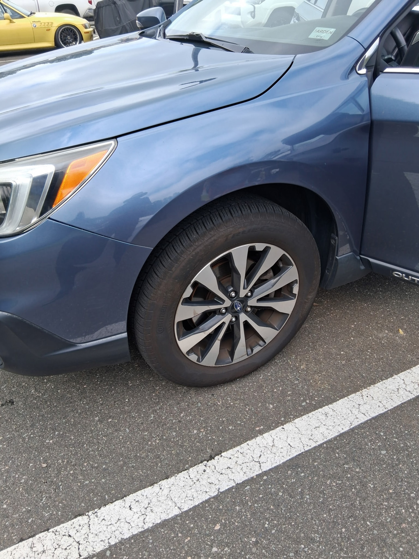 Polished front quarter panel and wheel of a blue Subaru Outback