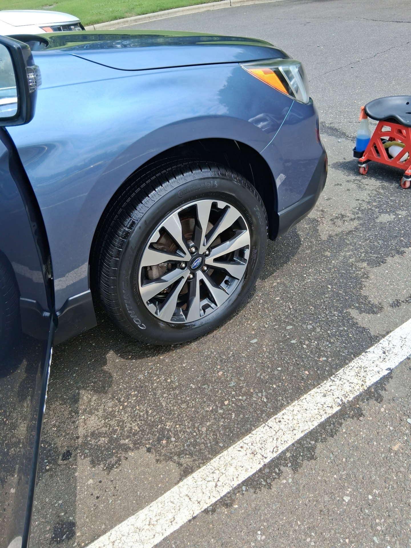 Cleaned wheel, tire, and fender of a blue Subaru Outback
